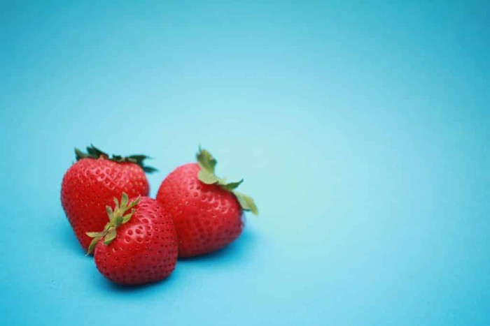 Three strawberries on blue background